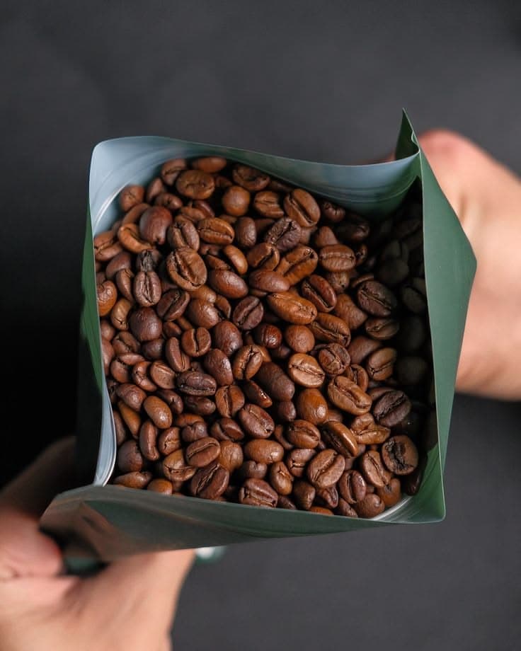 Hands holding an open bag of freshly roasted single-origin coffee beans